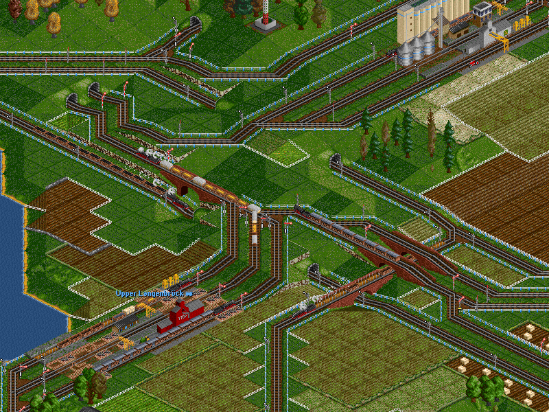 Navigating the heavy-traffic junction south-west of the factory. I've tried to give the coal trains lots of dedicated tracks, and prioritised the junctions whenever they meet with the important farm trains, which keep the goods trains running.